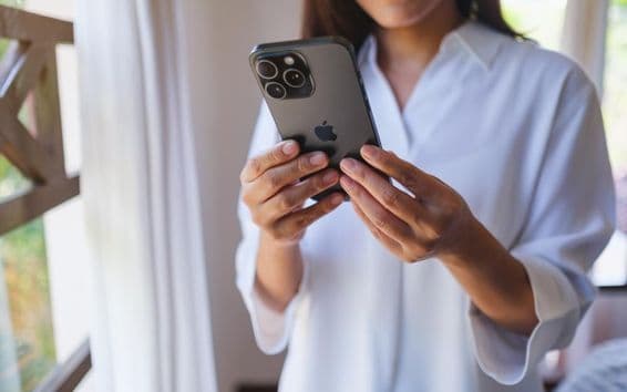 घर पर एक महिला आईफोन 15 प्रो मैक्स का उपयोग करते हुए।