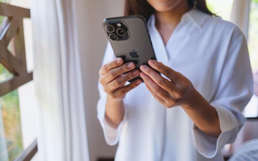 घर पर एक महिला आईफोन 15 प्रो मैक्स का उपयोग करते हुए।