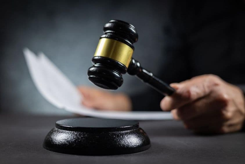 न्यायाधीश अदालत में दस्तावेज़ के साथ निर्णय की घोषणा करते हुए।