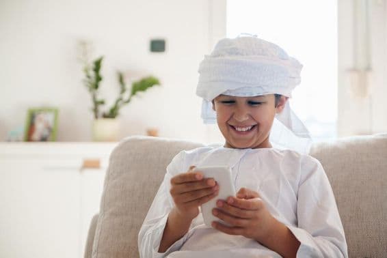 अरब लड़का घर में स्मार्टफोन का उपयोग कर रहा है।