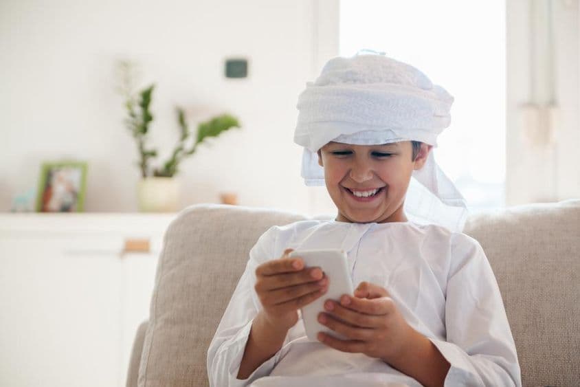 अरब लड़का घर में स्मार्टफोन का उपयोग कर रहा है।