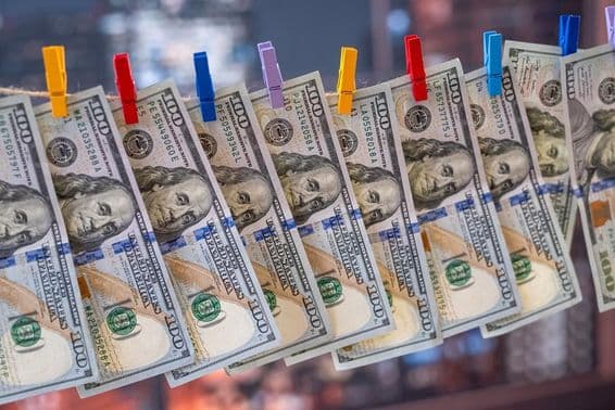 एक 100 अमेरिकी डॉलर का नोट लकड़ी के क्लिप के साथ कपड़े की रेखा पर लटका हुआ।