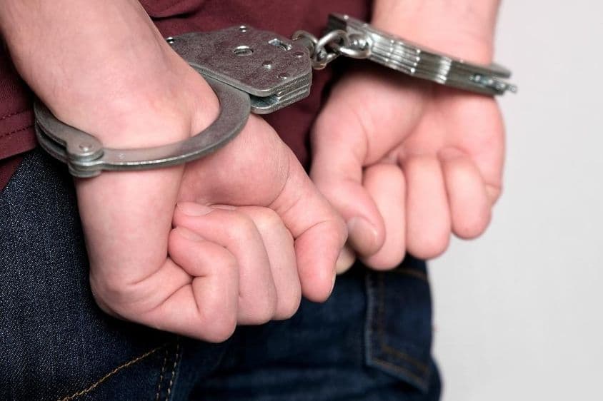 एक अपराधी हथकड़ी लगाकर गिरफ्तार हुआ।