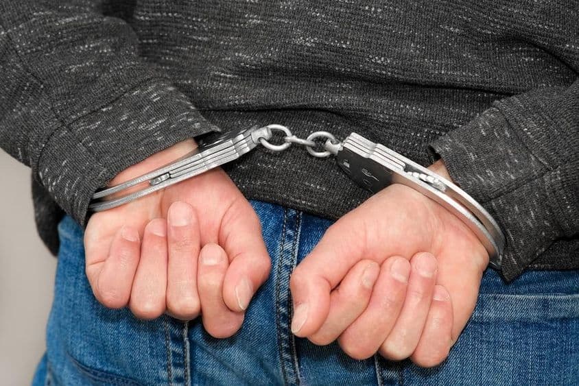 अपराधी हथकड़ी में अपराधों के लिए पकड़ा गया।