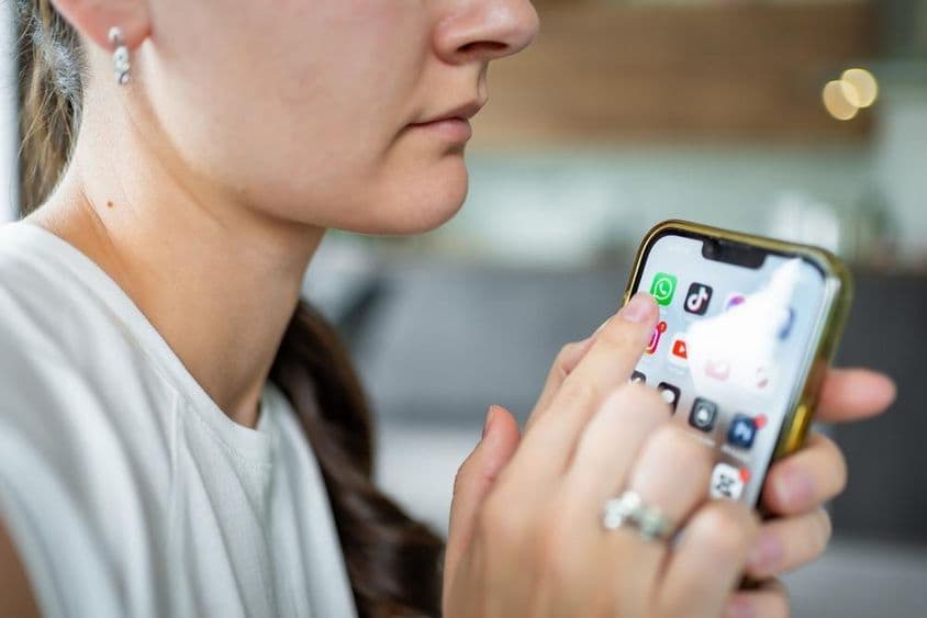 महिला अपने आईफोन पर व्हाट्सएप चैट एप्लिकेशन के साथ।