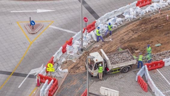 फुटपाथ मरम्मत प्रक्रिया में कई निर्माण श्रमिक और उपकरण फुटपाथ और कंक्रीट को तोड़ते हुए।