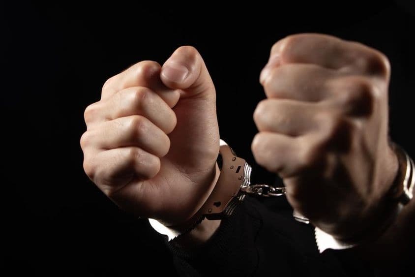 अपराधों के लिए गिरफ्तार किए गए हथकड़ी में लोग।
