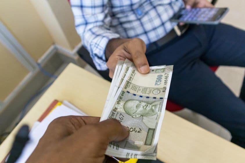 एक व्यक्ति दूसरे को ५००-रुपये का भारतीय नोट दे रहा है।