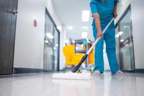 सफाईकर्मी हॉल के फर्श पर पोछा लगाती हुई।