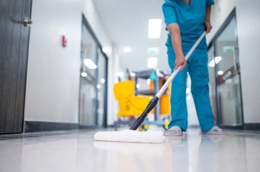 सफाईकर्मी हॉल के फर्श पर पोछा लगाती हुई।