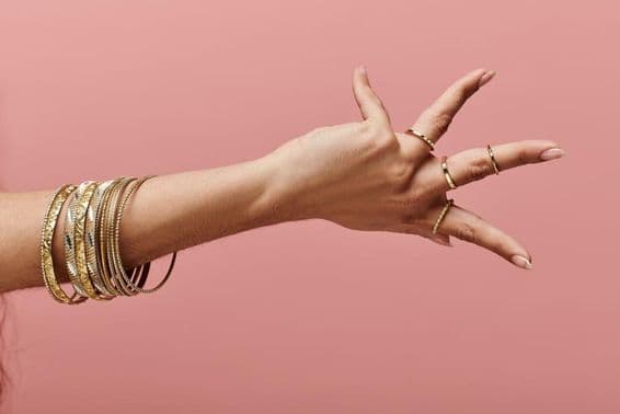 भारतीय महिला अपने हाथ पर सोने के कंगन के साथ सुंदरता में प्रस्तुत करती हुई।