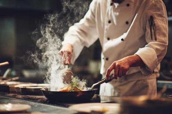 रसोई में खाना पकाते हुए एक शेफ।