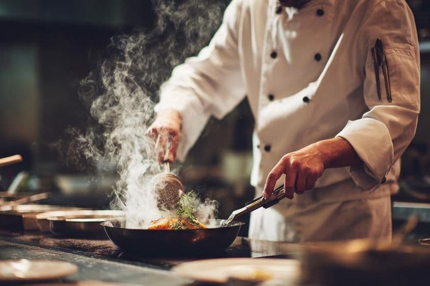 रसोई में खाना पकाते हुए एक शेफ।