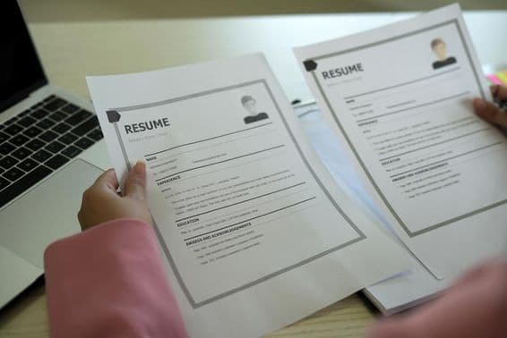 एक युवा एशियाई महिला एचआर प्रबंधक एक रेज़्यूमे पढ़ रही है।