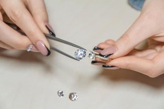 एक जौहरी महिला के हाथ गहना पत्थर पकड़े हुए।