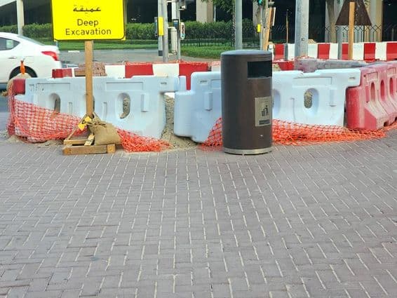 सड़क की मरम्मत प्लास्टिक बैरियर और एक नारंगी सुरक्षा जाल द्वारा घिरी हुई है।