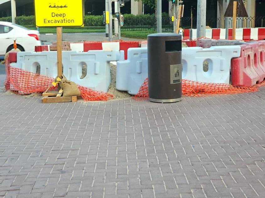 सड़क की मरम्मत प्लास्टिक बैरियर और एक नारंगी सुरक्षा जाल द्वारा घिरी हुई है।