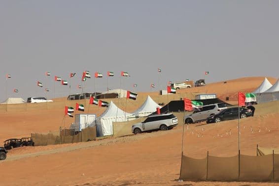 बड़े रेत के टीलों पर ऑफ-रोड गाड़ियाँ और जंगली कैम्पिंग।