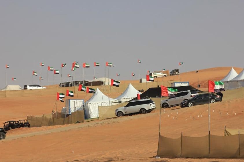 बड़े रेत के टीलों पर ऑफ-रोड गाड़ियाँ और जंगली कैम्पिंग।