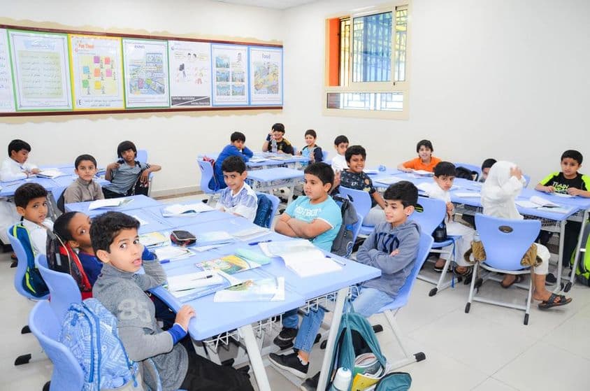 एक क्लासरूम जहाँ एक समूह छात्र और उनका शिक्षक पाठ में संलग्न हैं।