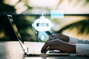 एक व्यक्ति लैपटॉप पर टाइप कर रहा है, जिसमें एक धुंधले बाहरी पृष्ठभूमि में चैटबॉट आइकन दिख रहा है।