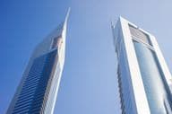 नीले आकाश के नीचे दो गगनचुंबी इमारतें।