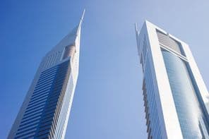 नीले आकाश के नीचे दो गगनचुंबी इमारतें।