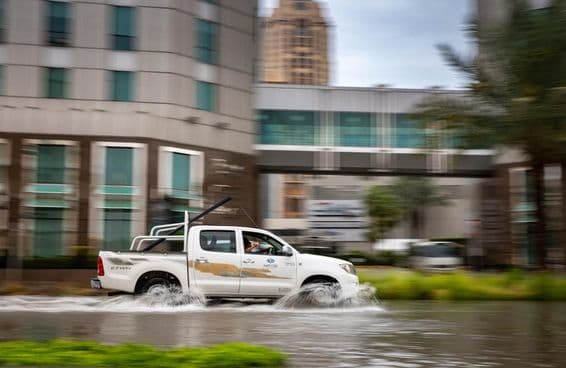 दुबई में बाढ़ग्रस्त सड़क पर गाड़ी चलाना।