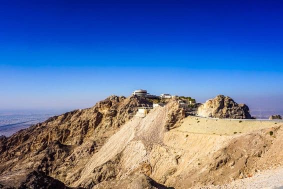 अल ऐन जबल हफीत पर्वत का दृश्य शिखरों और भवनों के साथ।