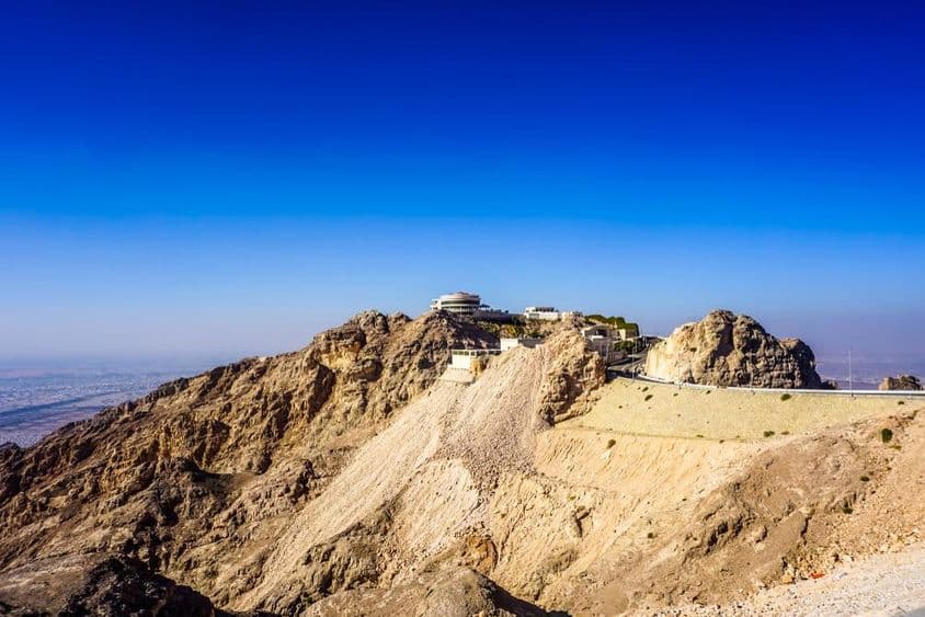 अल ऐन जबल हफीत पर्वत का दृश्य शिखरों और भवनों के साथ।