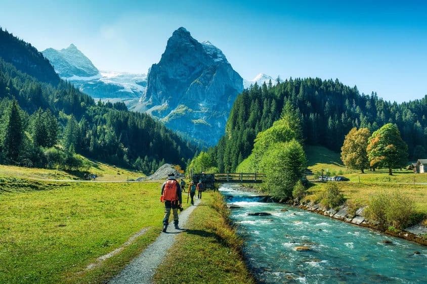 स्विट्जरलैंड के बर्न कैंटन में जंगल में एक नदी के किनारे चलते पर्यटकों का समूह।