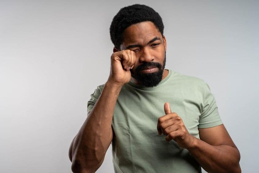 एक व्यक्ति अपनी आँखें असहजता से मल रहा है, जलन और थकान का अनुभव कर रहा है।