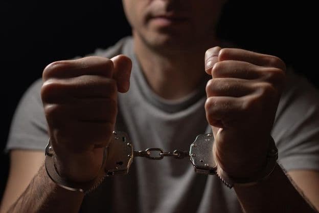 हाथ के सामने हथकड़ी में बांधे हुए।