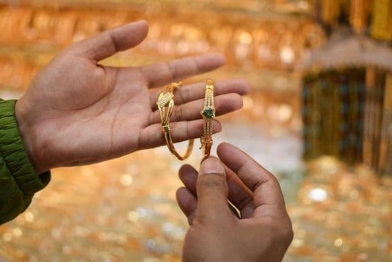एक हाथ पर एक लग्जरी सोने का ब्रेसलेट आज़माते हुए