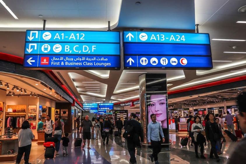 दुबई अंतरराष्ट्रीय हवाई अड्डे पर प्रस्थान गेट की ओर चलते हुए यात्री